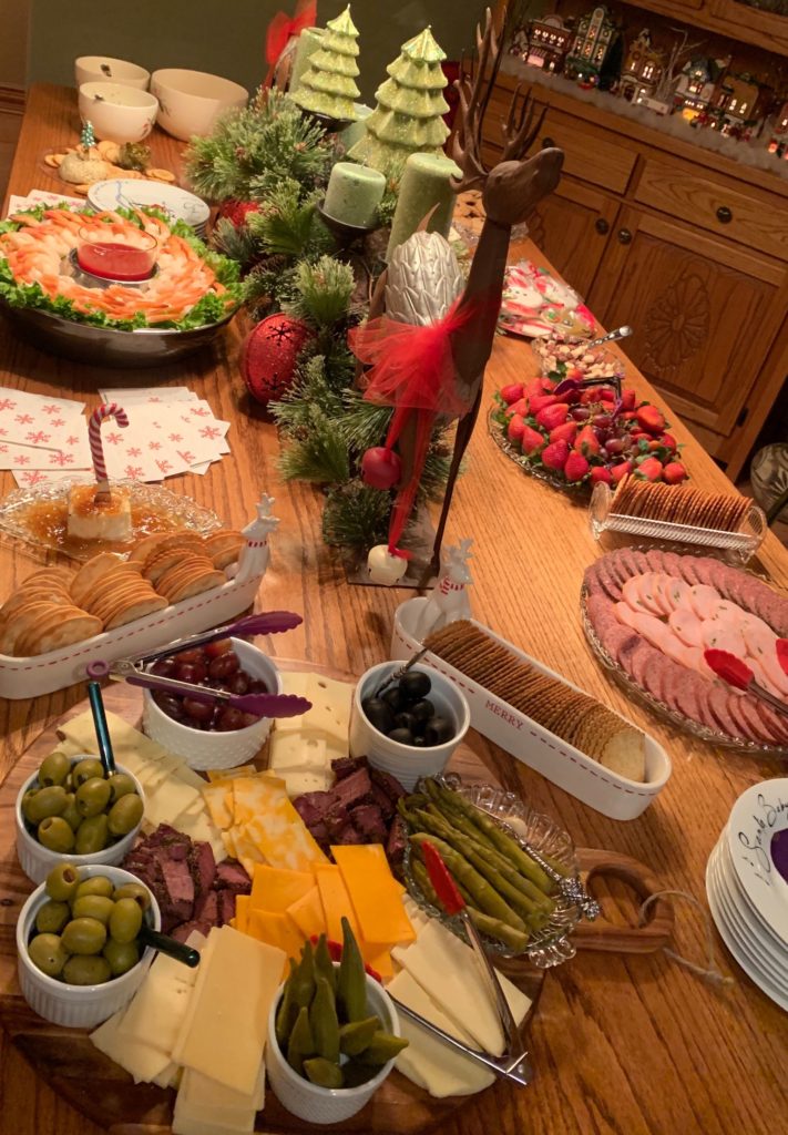A nice spread of healthy veggies, olives, meats and cheeses on a holiday decorated table.