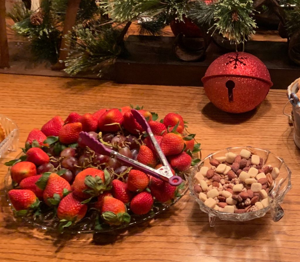 A dish of bright, beautiful strawberries  and grapes next to a dish of mixed nuts with sea salt. 