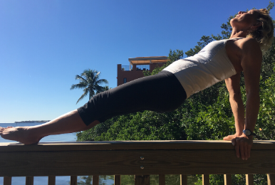 Jennifer in Reverse Plank Pose on top of a rail by the bay where she lives and coaches clients.