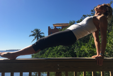 Jennifer Stark demonstrating revers plank atop of the railing of a dock