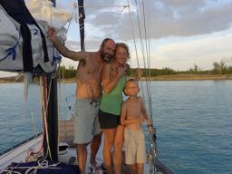 Stark family standing on our sailboat home, a life of freedom.
