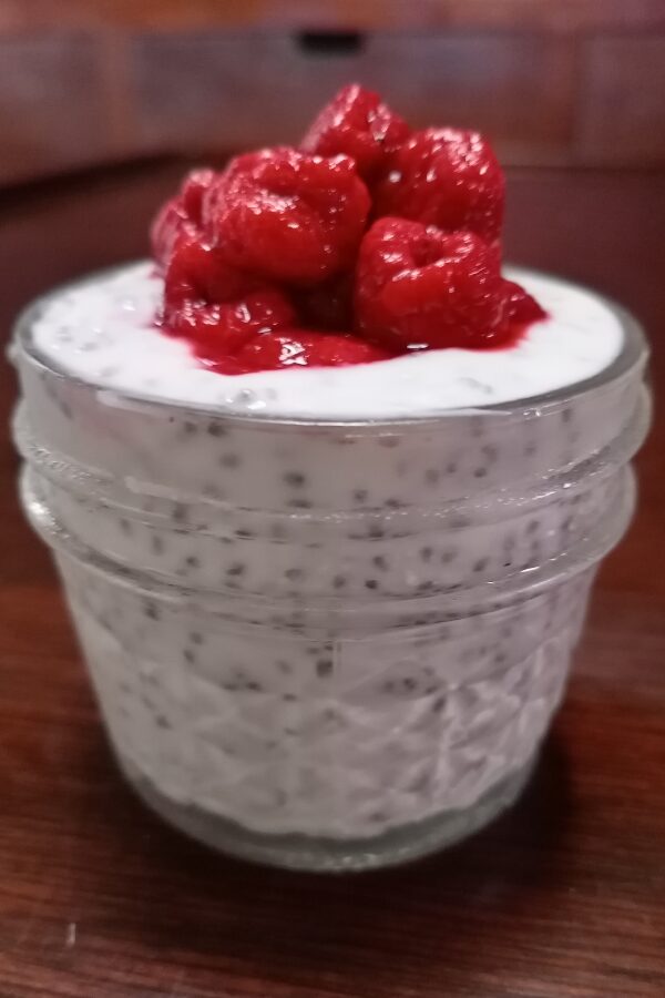 Delectible raspberry chia seed yogurt parfait with fresh, bright red raspberries on top.